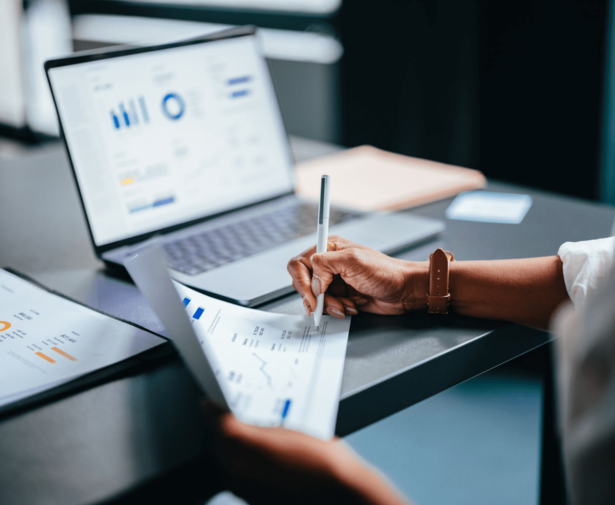 Analyzing financial charts on laptop and paper